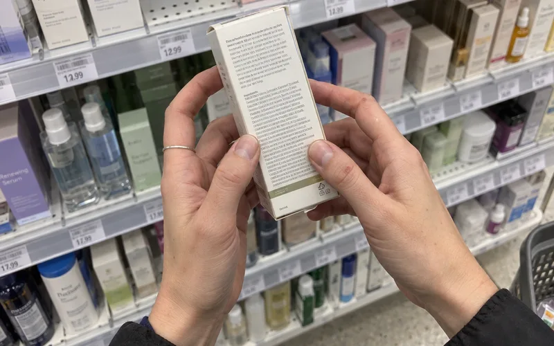 Hands holding a skincare box to check the retinol ingredient list in a drugstore