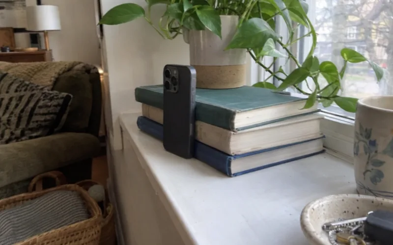 Smartphone propped against books on a windowsill, set up to take a retinol progress photo in daylight