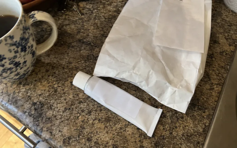 Prescription retinoid cream tube on a kitchen counter next to a pharmacy bag