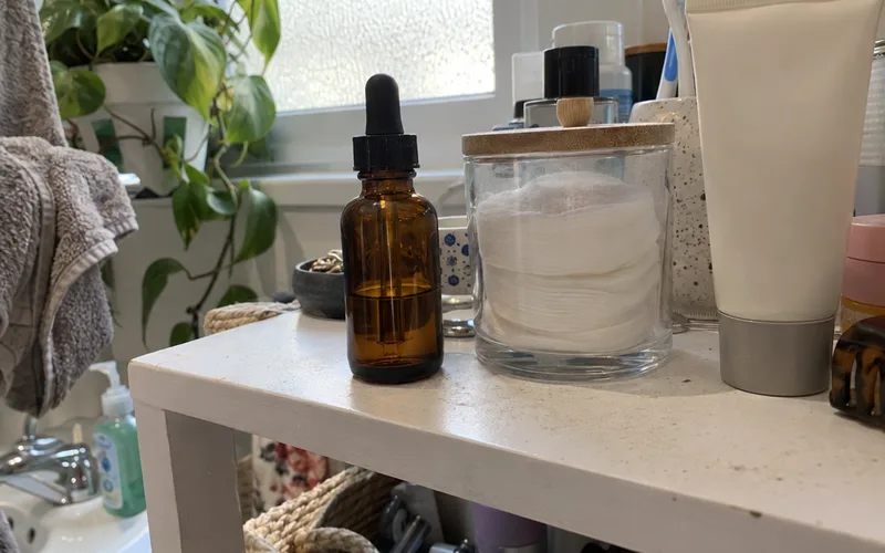 Retinol serum dropper bottle on a bathroom shelf next to moisturizer